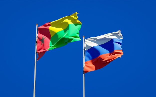 Beaux drapeaux nationaux de la Russie et de la Guinée-Bissau ensemble sur le ciel bleu. Illustration 3D