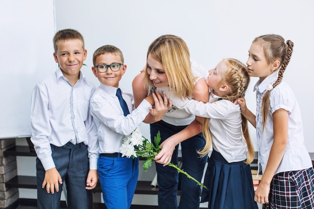 Beaux enfants écoliers avec des fleurs pour les enseignants à l'école en vacances