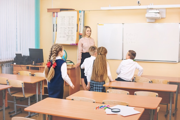 De beaux enfants-étudiants ensemble dans la salle de classe à l'école vont en classe à l'enseignant