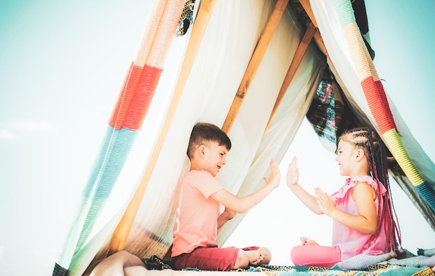 De beaux enfants mignons jouent dans une tente Les enfants jouent avec une tente tipi