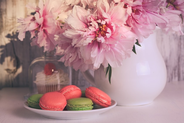 Beaux gâteaux et macarons avec du café et des fleurs