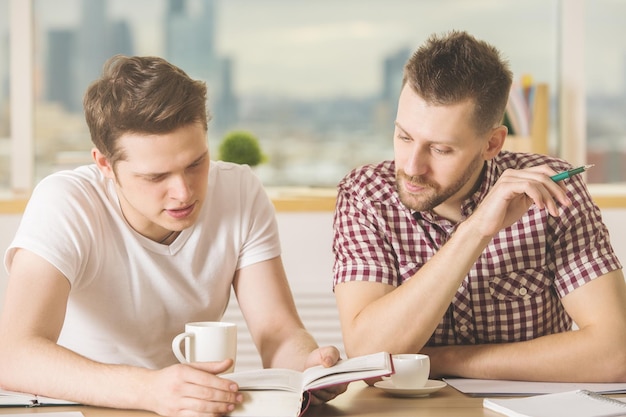 Beaux hommes d'affaires lisant un livre et faisant de la paperasse