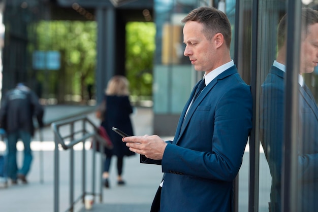 Beaux hommes d'affaires utilisant un téléphone en plein air