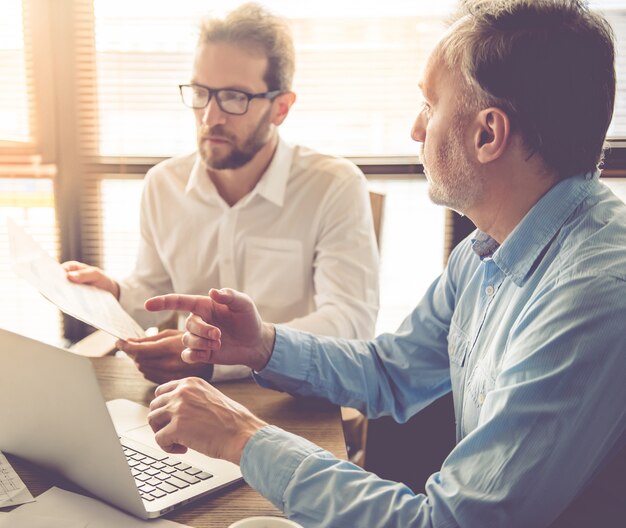 Les beaux hommes d'affaires utilisent un ordinateur portable.