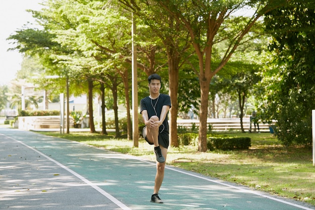 Les beaux hommes asiatiques se réchauffent avant de marcher et de faire du jogging dans le parc le matin.