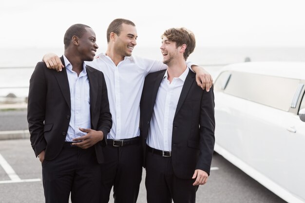 Beaux hommes posant à côté d'une limousine