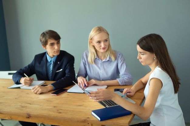 beaux jeunes au bureau à la table avec un ordinateur portable