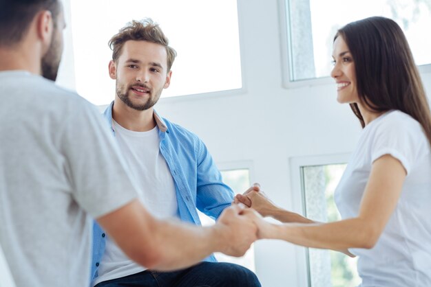 De beaux jeunes gens agréables se tenant la main et établissant la confiance entre eux tout en apprenant à être une équipe