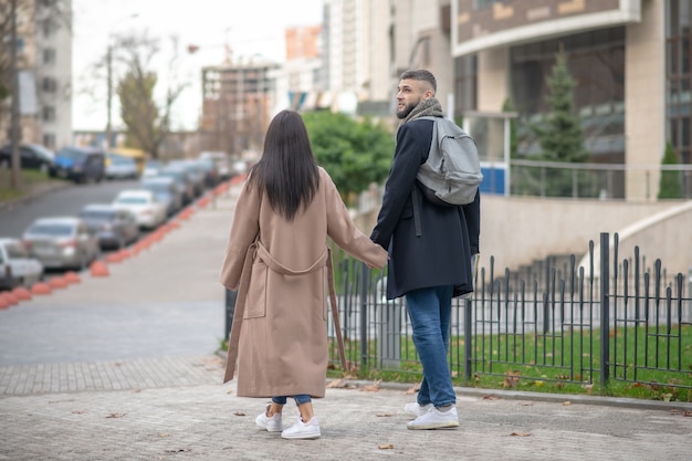 Beaux jeunes marchant main par main tout en montrant leurs sentiments