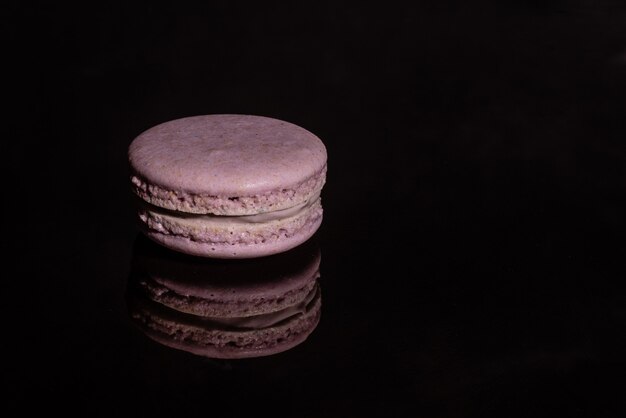 Beaux macarons roses savoureux sur un fond sombre