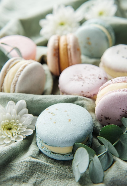 Photo beaux macarons savoureux colorés et fleurs blanches sur fond textile