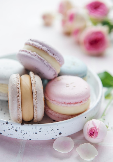 Beaux macarons savoureux colorés et roses roses sur un fond rose de tuile