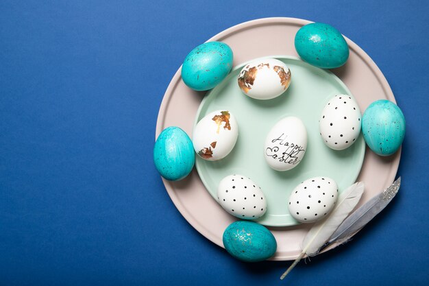 Beaux oeufs de Pâques sur une plaque sur un bleu