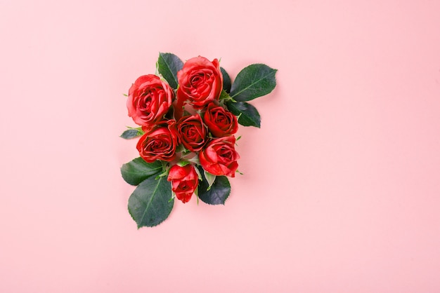 Beaux petits boutons de rose, pétales et feuilles de rose sur un fond légèrement rose. Concept de la Saint-Valentin