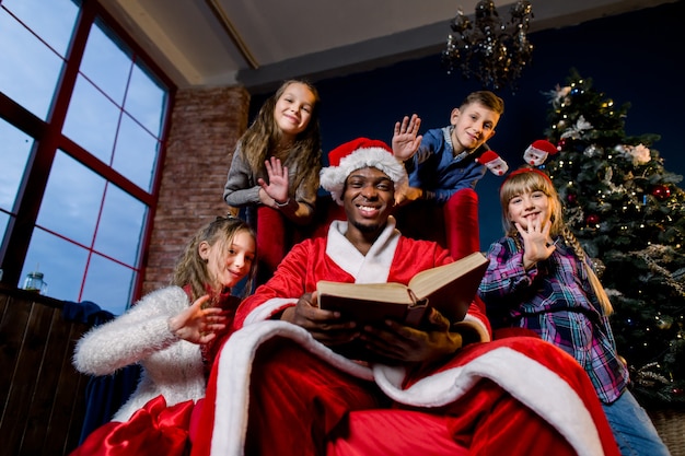 De beaux petits enfants écoutent l'histoire que le Père Noël lit