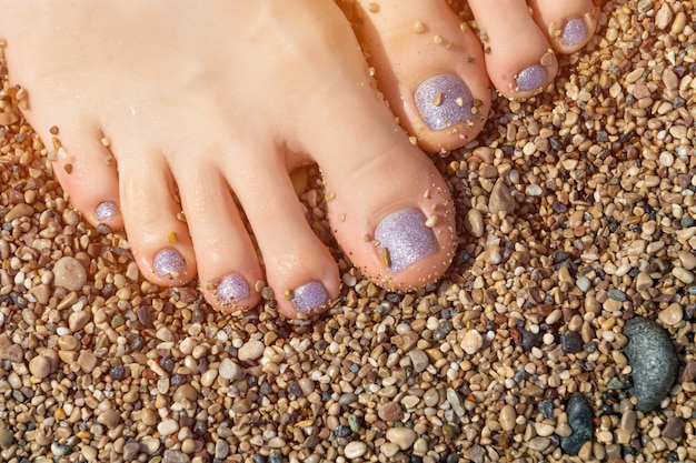 Beaux pieds féminins avec pédicure à paillettes bleues