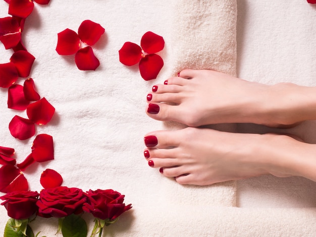 Photo beaux pieds féminins et pétales de rose spa et concept de soins de la peau