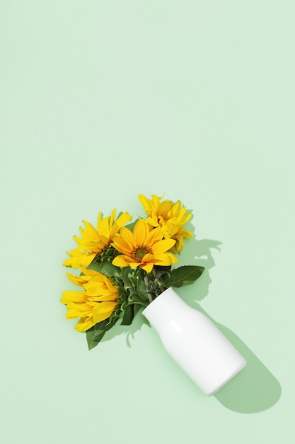 Beaux tournesols dans un vase blanc sur papier de couleur menthe.
