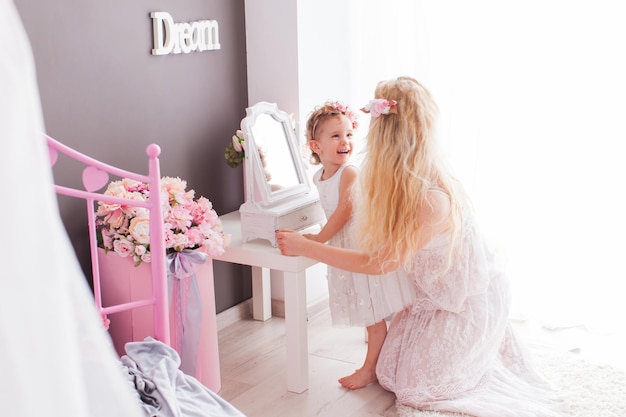 Beaux visages d'une femme et d'une petite fille, reflétés dans un miroir, avec des bouquets de fleurs des deux côtés