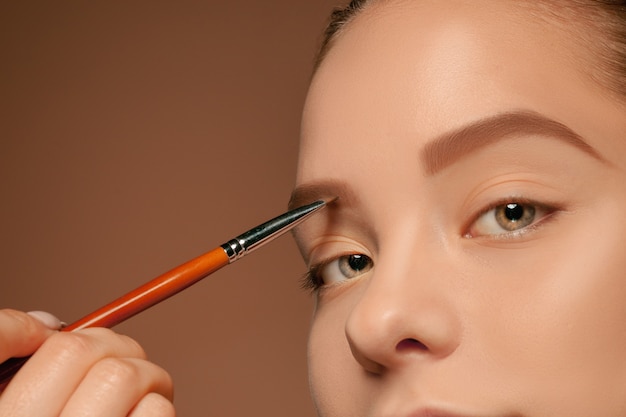 Beaux yeux féminins avec maquillage et pinceau sur fond de studio