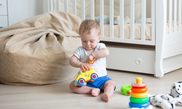 Bébé de 10 mois jouant sur le sol avec petite voiture et blocs