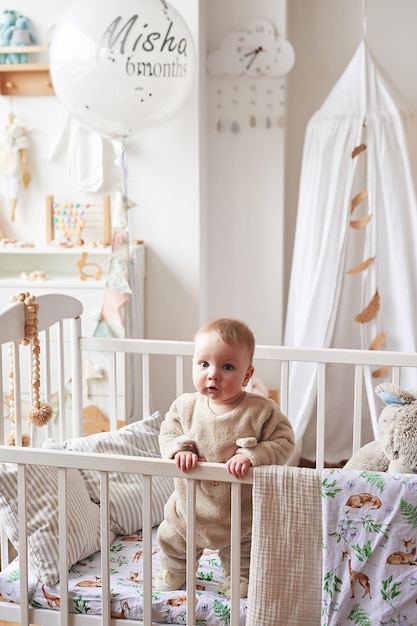 Bébé de 6 mois debout dans un berceau dans la chambre des enfants. Bonne maternité et paternité. Maternité et clinique. Fête des pères et des mères. Développement de la petite enfance, crèche