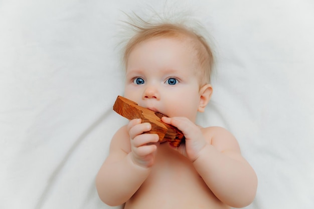 Bébé de 6 mois tient dans ses mains un jouet de dentition en bois allongé dans un berceau dans une chambre d'enfant