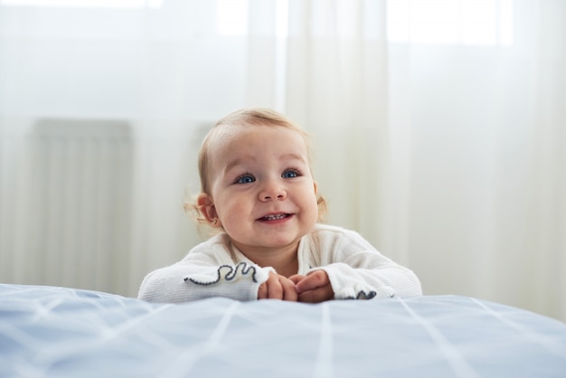 Un bébé âgé d'un an assis sur le sol souriant sur blanc