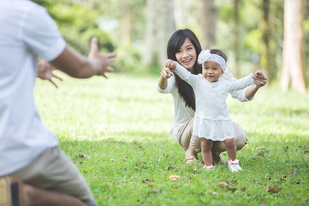 Bébé apprend à marcher avec ses parents dans le parc