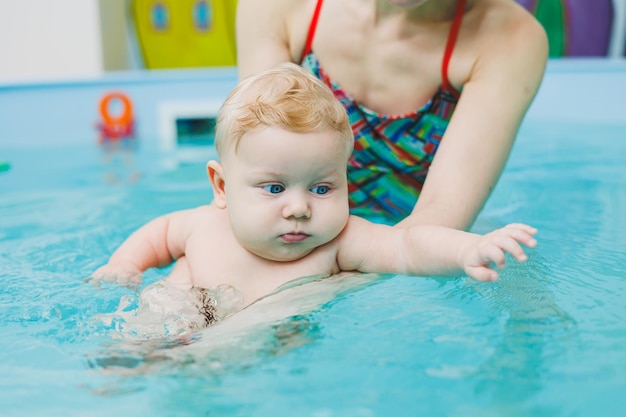 Un bébé apprend à nager dans une piscine avec un entraîneur Bébé apprenant à nager Développement de l'enfant