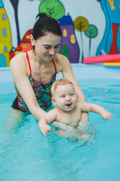 Un bébé apprend à nager dans une piscine avec un entraîneur Bébé apprenant à nager Développement de l'enfant