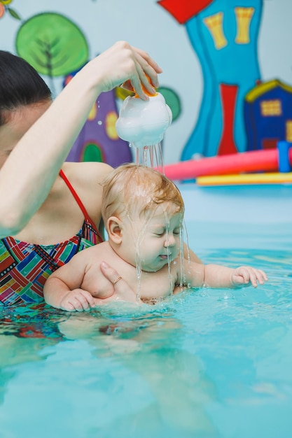 Un bébé apprend à nager dans une piscine avec un entraîneur Un bébé apprend à nager Développement de l'enfant