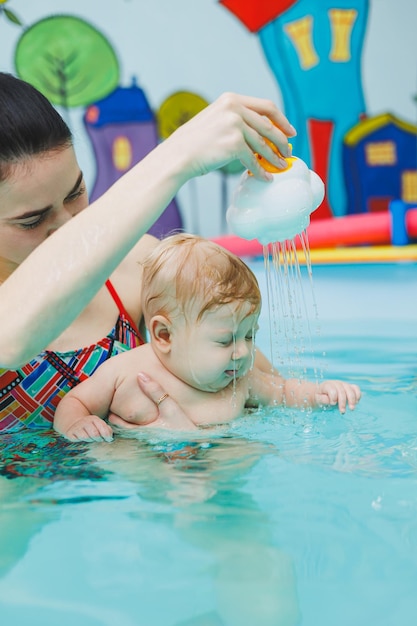 Un bébé apprend à nager dans une piscine avec un entraîneur Un bébé apprend à nager Développement de l'enfant