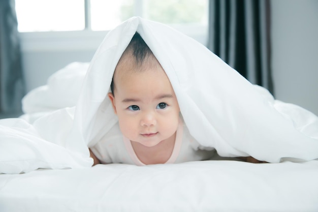 Bébé asiatique allongé sur le lit avec une couverture douce à l'intérieur mignon petit nouveau-né asiatique