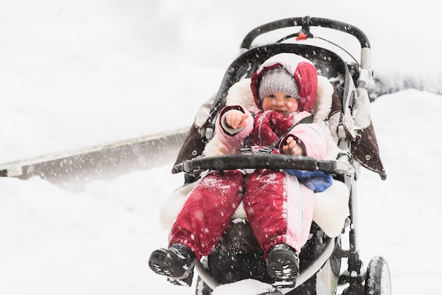 Bébé assis dans une poussette pendant la neige