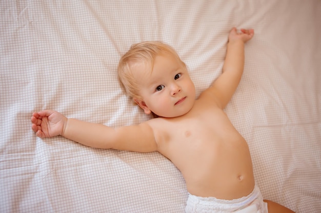 bébé assis dans son lit sur le linge de lit en couches