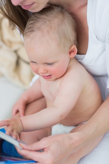 Bébé assis sur sa mère en regardant un livre