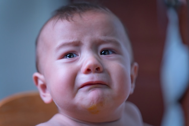 Bébé assis triste et pleurant dans la chambre