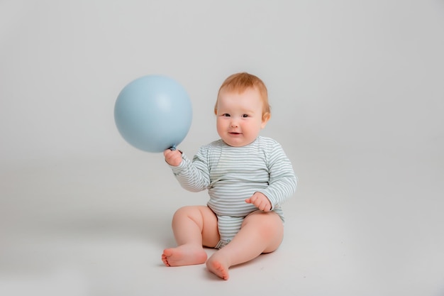 Bébé avec un ballon bleu sur fond blanc