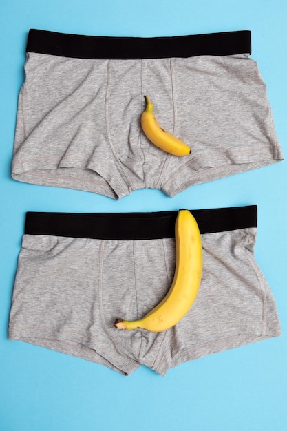 Bébé banane comparer la taille avec une grosse banane sur une culotte masculine sur fond bleu