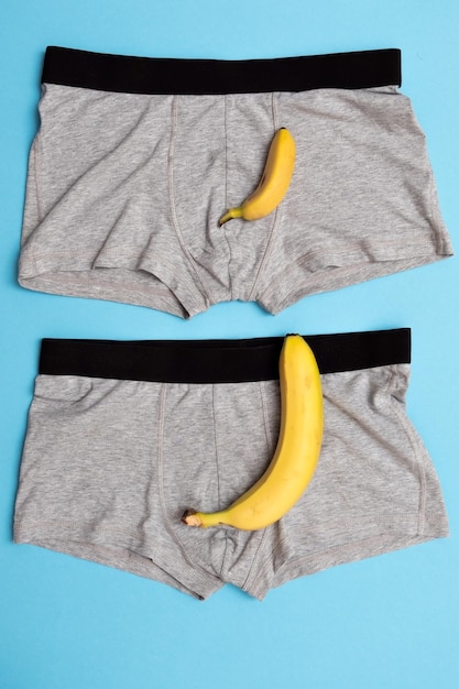 Bébé banane comparer la taille avec une grosse banane sur une culotte masculine sur fond bleu