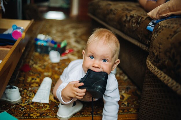 Bébé bébé enfant garçon âgé de six mois prend sa chaussure dans la bouche.