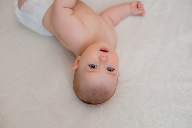 Bébé en bonne santé sourit allongé sur le lit à la maison