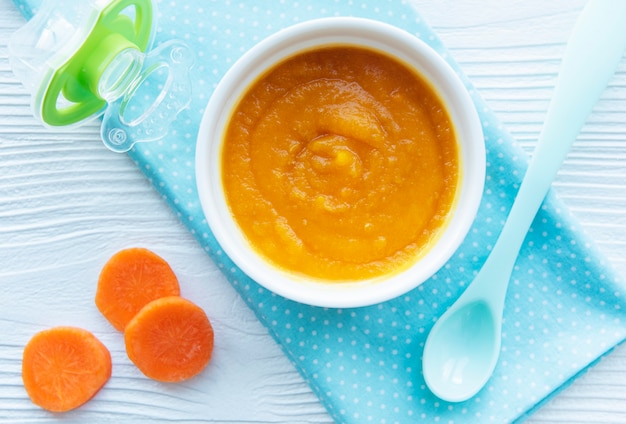 Bébé carotte en purée avec cuillère dans un bol, nourriture pour bébé