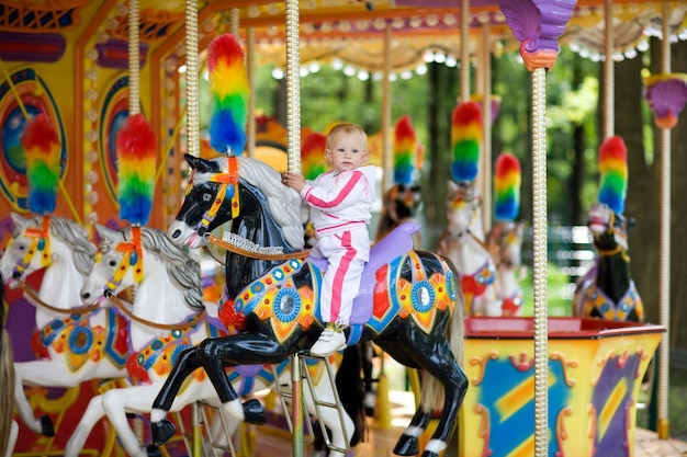 un bébé sur un carrousel avec un arc-en-ciel sur le dessus