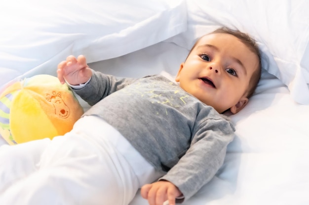 Bébé caucasien de 5 mois souriant dans un lit blanc vient de se réveiller