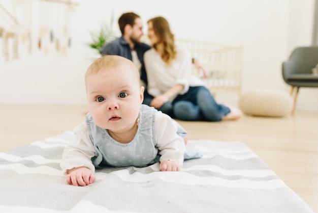 Bébé caucasien rampant sur le sol de la pépinière avec ses parents