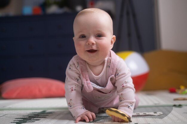 Bébé caucasien de six mois sur le sol avec un jouet