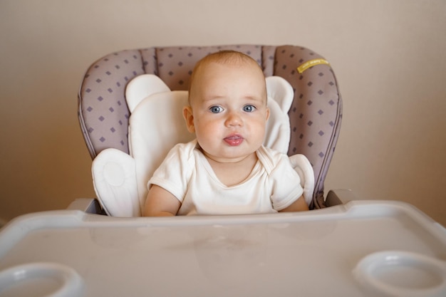 bébé sur une chaise bébé dans un body blanc