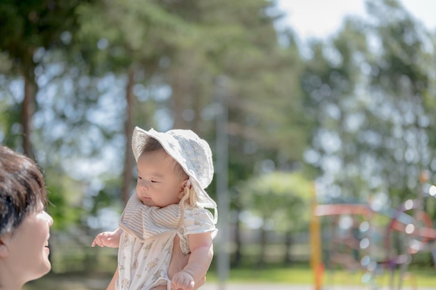 Un bébé avec un chapeau marche avec sa mère.